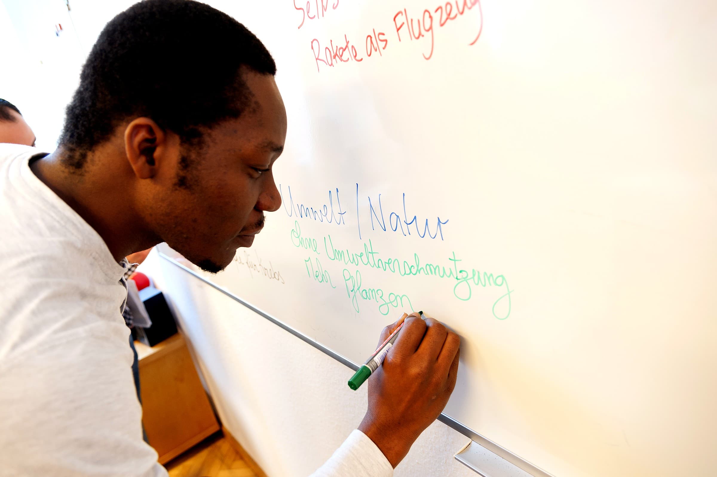 CASA learner writing German vocabulary on a classroom whiteboard
